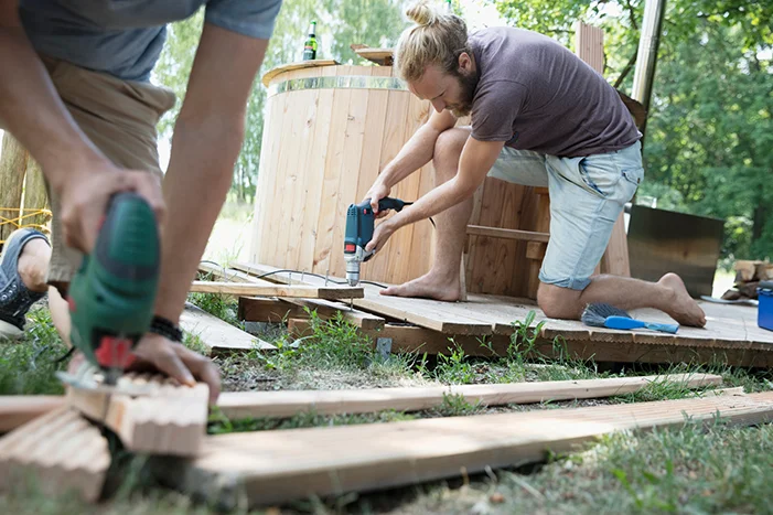 Personen bauen Holzterrasse mit Bohrmaschine und Stichsäge